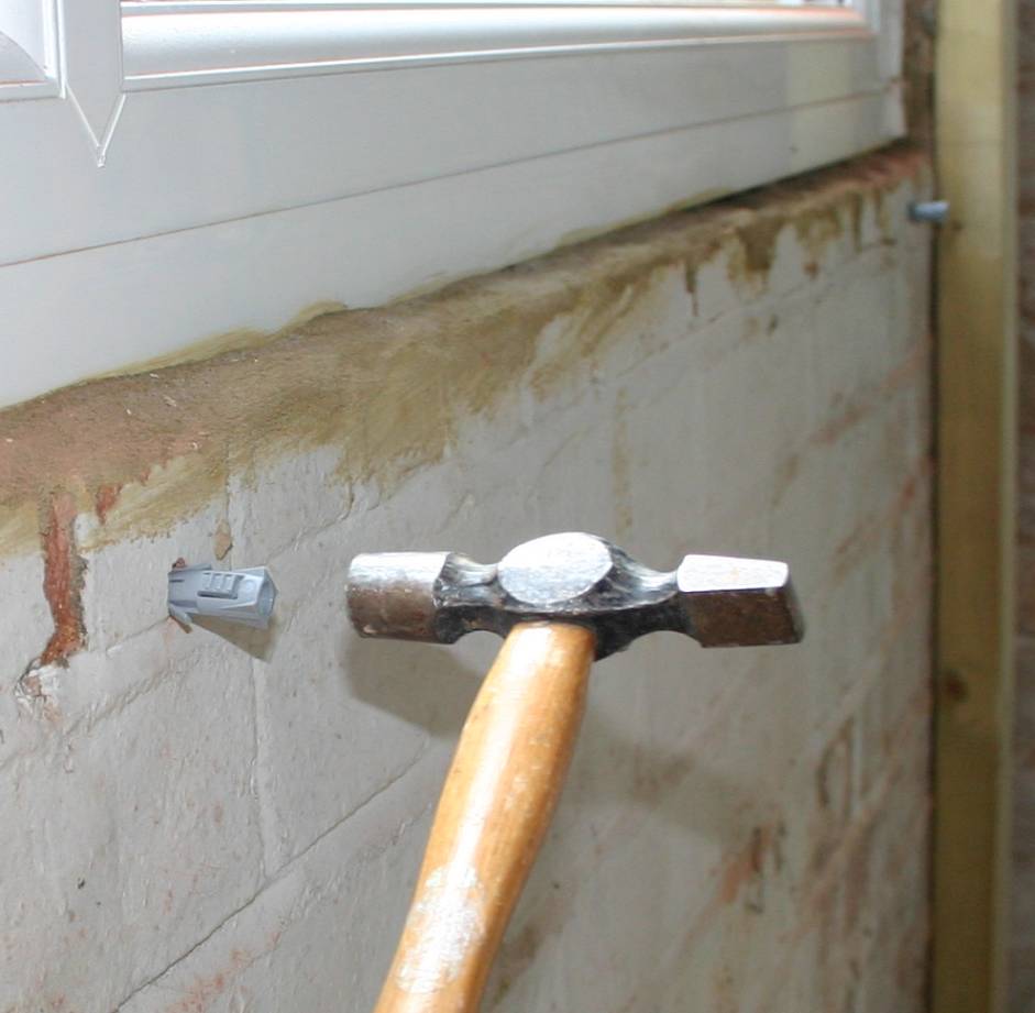 Tapping the plastic plug into place into the hole in the brickwork.