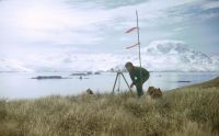 Plane table surveying on Albatross Crest (spot height 126), Annenkov Island. The metal poles with red polythene ties were used as markers for sighting between survey stations. November 1972.