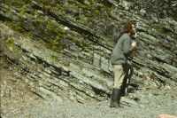 Tim Pettigrew on the beach on the north-east coast of Annenkov Island (near the landing beach), using a Jacob's Staff and Abney level to measure up a sequence of tuffs and tuffaceous mudstones exposed in the cliffs. January 1973.