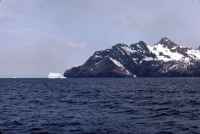 View from the deck of the RRS John Biscoe of an iceberg and folding in the rocks of the Cumberland Bay Formation on the north-eastern coast of South Georgia. Afternoon of the 7th November 1972.