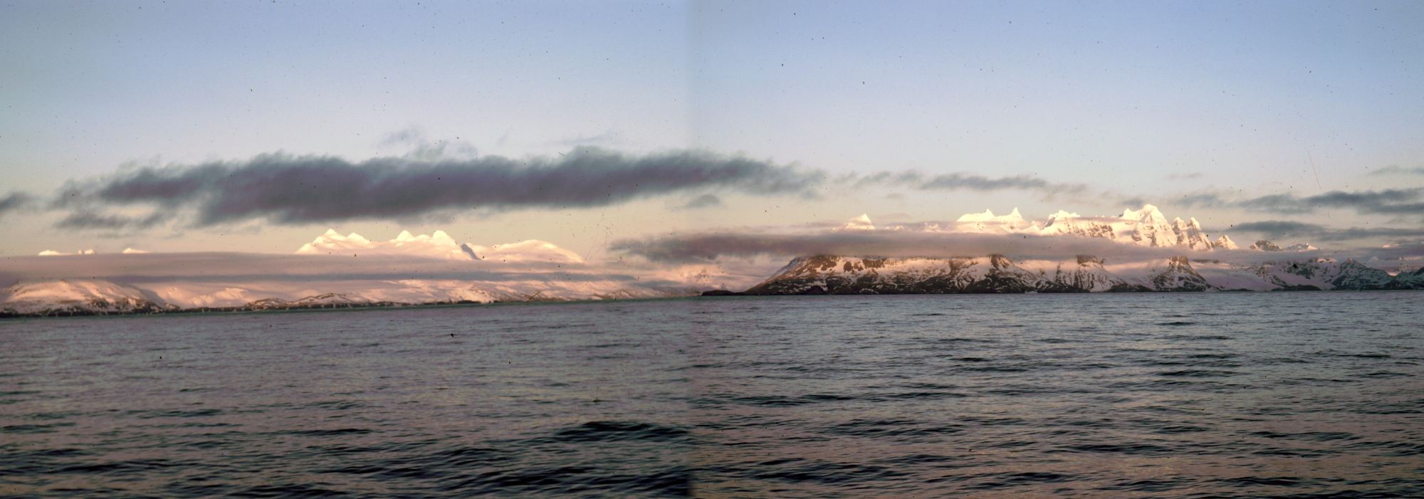 View from the deck of the RRS John Biscoe, looking north-east at the sun-lit peaks of South Georgia, at Queen Maud Bay on the evening of 13th November 1972.