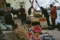 The RRS John Biscoe off the north-eastern coast of Annenkov Island (visible in the background). Equipment ready for transport ashore includes wooden sledging boxes (food). Personnel, left to right; Roger Scott, two crew members, Pete Crockford (Bosun), Eric Lawther. Landing craft (Gemini) just visible on extreme right of picture. 4th November 1972.