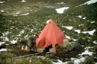 The three man pyramid tent used by Eric Lawther & Tim Pettigrew from 14th November 1972 until 15th April 1973, during their 5 month survey of Annenkov Island. The sledging (food) ration boxes placed on the tent valences helped to ensure stability of the tent in high winds. As the food was consumed and the boxes emptied, they were filled with rock specimens collected during the geological survey. Eric Lawther pictured outside the tent. November 1972.